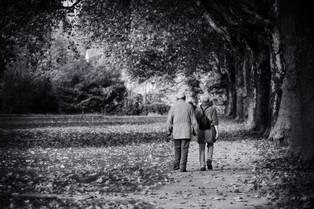 Čiernobiela fotografia staršieho páru kráčajúceho po tichej aleji stromov. Hlavný vizuál sekcie O nás symbolizujúci životnú cestu, spomienky a dôstojný prístup Podjavorinského krematória k poslednej rozlúčke.